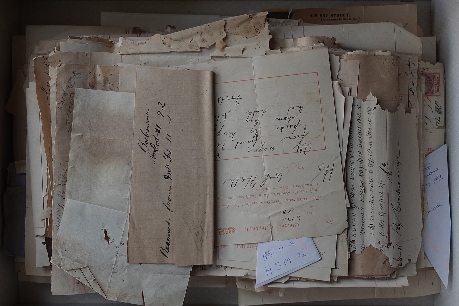 Une boîte en carton bleue remplie de vieilles lettres et de télégrammes jaunis, vue de dessus