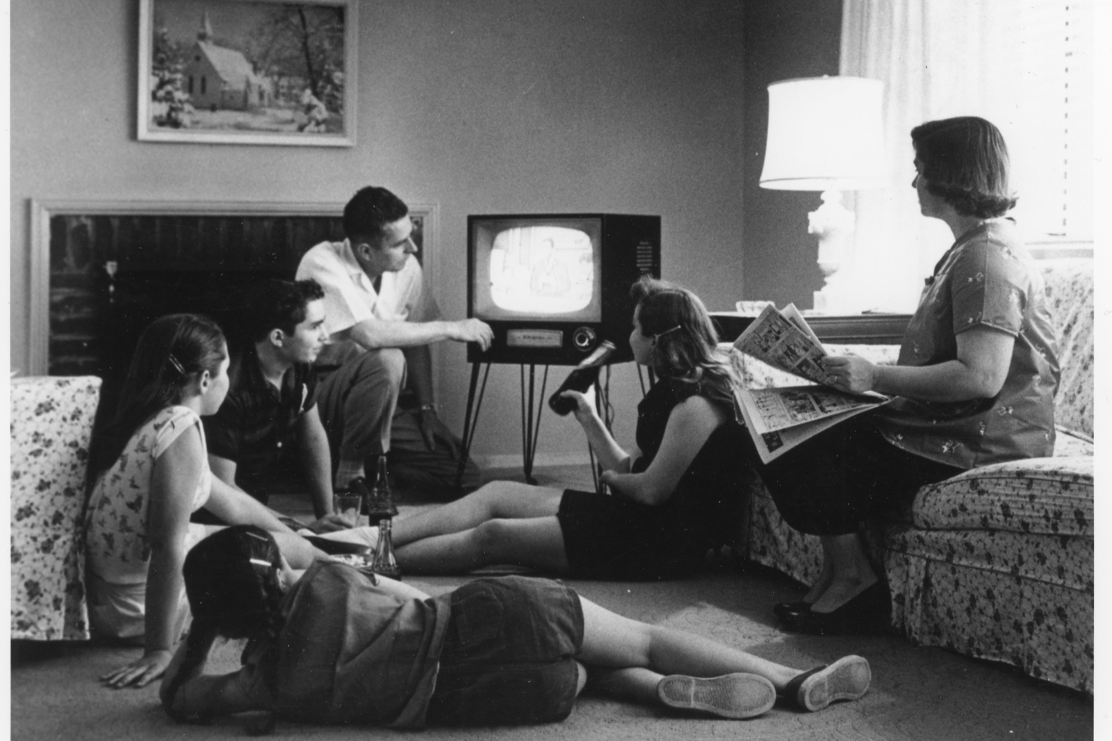 Une famille américaine réunie dans son salon devant un poste de télévision, vers 1958, les enfants assis au sol et la mère sur le canapé